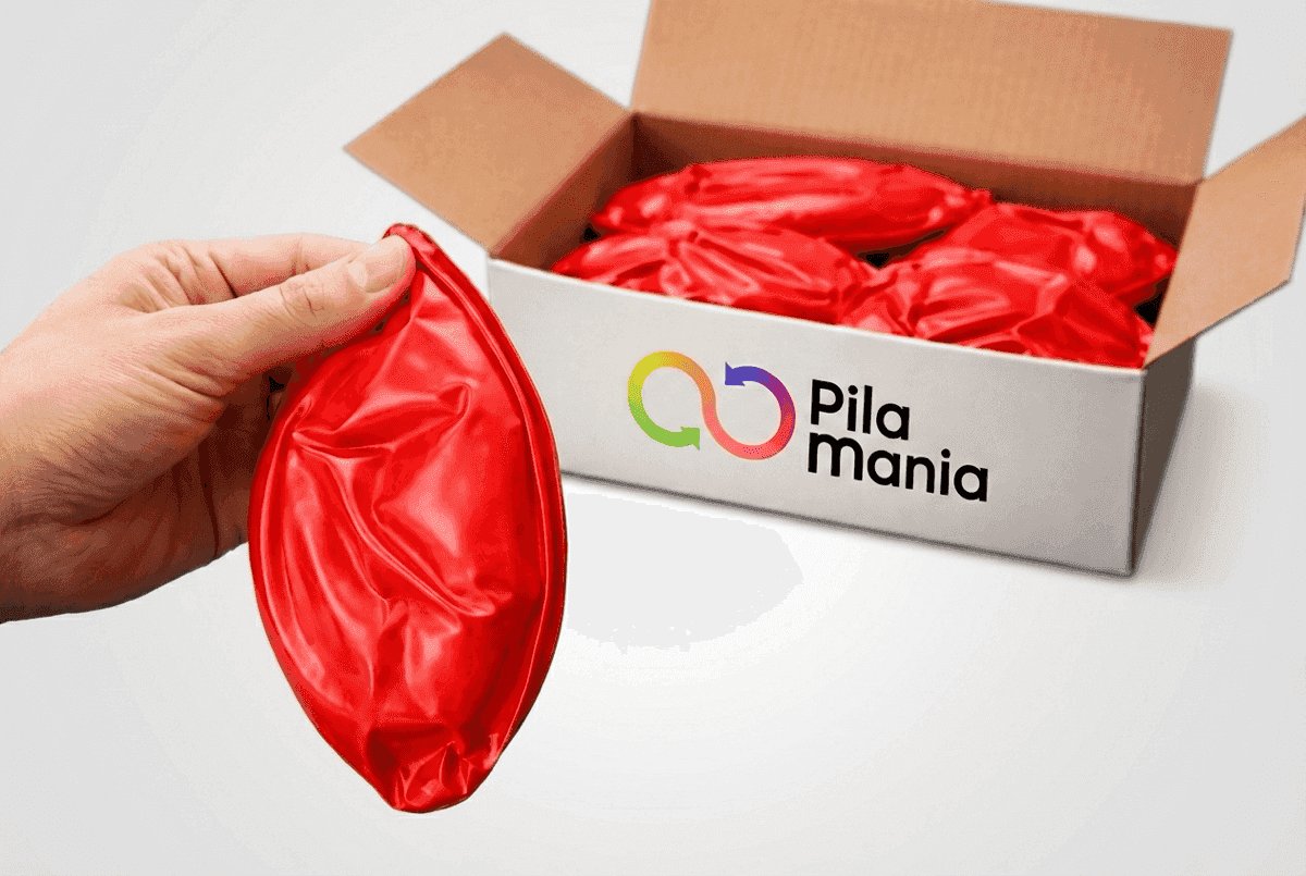 Mano sosteniendo una bola de PVC vacía sobre una caja con múltiples bolas planas